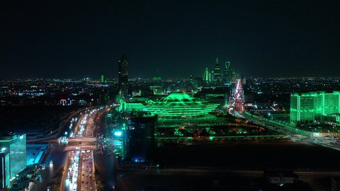 Transportation and traffic movement on the main streets and roads in the Kingdom of Saudi Arabia, aerial drone footage of organized traffic in the capital, the growth and development of infrastructure, and towers lit up in green to celebrate Saudi National Day in Riyadh.