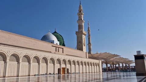 The outer courtyard of the Prophet's Mosque in Medina, Saudi Arabia, the architectural art of the minarets and the green dome, Islamic holy places, a sacred religious landmark during the day