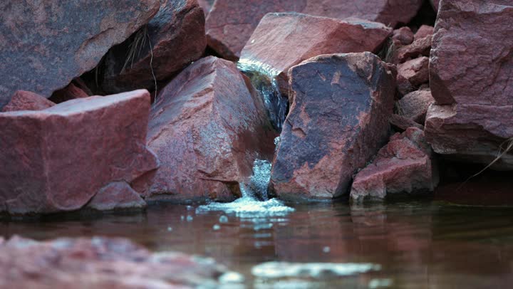 The flow of pure water in the city of Hail in the Kingdom of Saudi Arabia, the flow of water between rocks and stones, ancient historical folk monuments, a small water waterfall, tourist attractions in Saudi Arabia