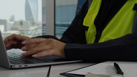 مهارة الكتابة السريعة على لوحة المفاتيح ،مفهوم الهندسة والإنشاءات المعمارية، تصوير مقرب  لأيدي مهندسة عربية خليجية سعودية ترتدي سترة الوقاية تقوم بالعمل عبر جهاز الحاسوب، مهن ووظائف مكتبية نسائية، استخدام الأجهزة التقنية الحديثة