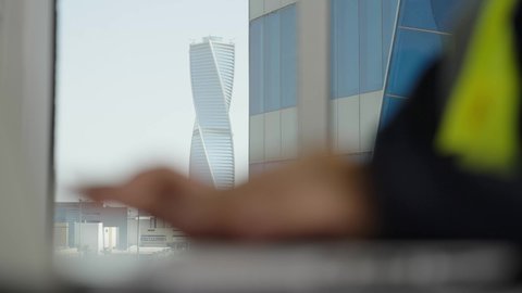 امتلاك مهارة الكتابة السريعة على لوحة المفاتيح ،مفهوم الهندسة والإنشاءات المعمارية، تصوير مقرب  لأيدي مهندسة عربية خليجية سعودية ترتدي سترة الوقاية تقوم بالعمل عبر الحاسوب، مهن ووظائف مكتبية نسائية، استخدام الأجهزة التقنية الحديثة،خلفية الأبراج وناطحات السحاب