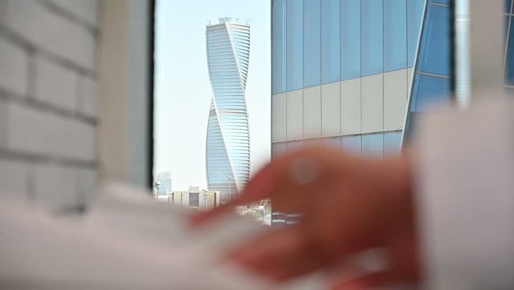 متابعة مخطط المشروع الهندسي وتدقيقه, مفهوم الهندسة والإنشاءات المعمارية، مشاريع إعمارية سعودية وطنية، الاهتمام بالتطور العمراني بسواعد المهندسين السعوديين, مهندس عربي خليجي سعودي يرتدي سترة العمل وخوذة الحماية البيضاء ينجز المهام اليومية في المكتب