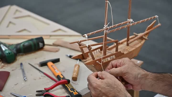 الشغف في ممارسة مهنة الغزل و النسج, تصوير مقرب لرجل عربي خليجي سعودي يقوم بحياكة وغزل الانسجة والقماش, حرفة يدوية تاريخيه, المحافظة على التراث الشعبي السعودي، صناعة المشالح باستخدام الخيوط الملونة