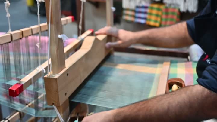 صناعة المشالح باستخدام الخيوط الملونة، الشغف في ممارسة مهنة الغزل و النسج, تصوير مقرب لرجل عربي خليجي سعودي يقوم بحياكة وغزل الانسجة والقماش, حرفة يدوية تاريخيه, المحافظة على التراث الشعبي السعودي