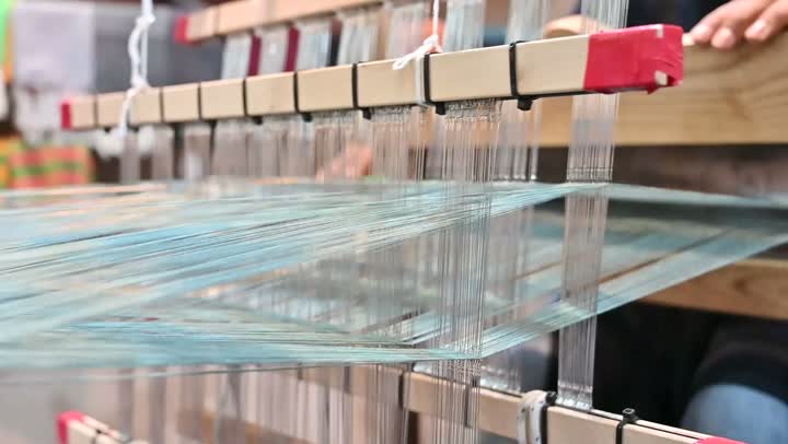 صناعة المشالح باستخدام الخيوط الملونة، الشغف في ممارسة مهنة الغزل و النسج, تصوير مقرب لرجل عربي خليجي سعودي يقوم بحياكة وغزل الانسجة والقماش, حرفة يدوية تاريخيه, المحافظة على التراث الشعبي السعودي