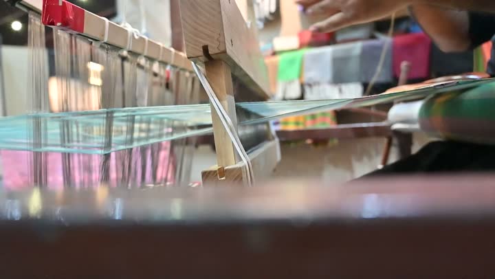 الشغف في ممارسة مهنة الغزل و النسج, تصوير مقرب لرجل عربي خليجي سعودي يقوم بحياكة وغزل الانسجة والقماش, حرفة يدوية تاريخيه, المحافظة على التراث الشعبي السعودي، صناعة المشالح باستخدام الخيوط الملونة