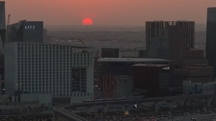 Economic and urban renaissance, aerial drone footage of Riyadh's skyline at sunset, modern and sophisticated towers and skyscrapers, famous commercial and economic landmarks in the Saudi capital, the illuminated King Abdullah Financial District (KAFD)
