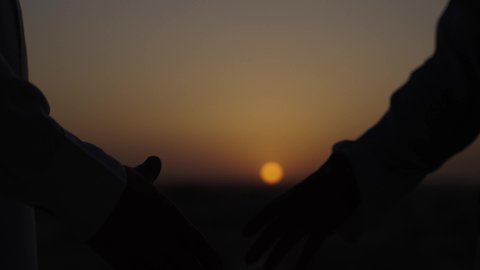 تعارف وصداقات وبناء علاقات اجتماعية، صفقات عمل جديدة ناجحة بين رجال الأعمال، الخروج في الهواء الطلق، الاتفاق والشراكة على الأعمال والمشاريع التجارية، تصوير مقرب لأيدي رجلان يقومان بمصافحة بعضهما، خلفية غروب الشمس