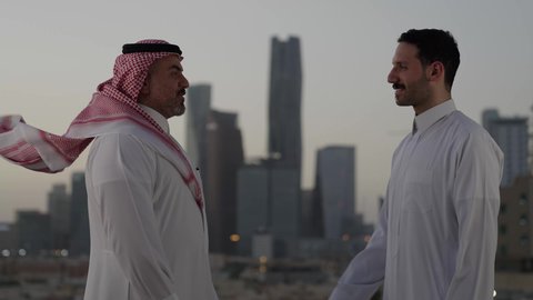 الاتفاق والشراكة على الأعمال والمشاريع التجارية، تعارف وصداقات وبناء علاقات اجتماعية، صفقات عمل جديدة ناجحة بين رجال الأعمال، الخروج في الهواء الطلق، رجلان عربيان خليجيان سعوديان يقومان بمصافحة بعضهما، خلفية الابراج وناطحات السحاب في الرياض