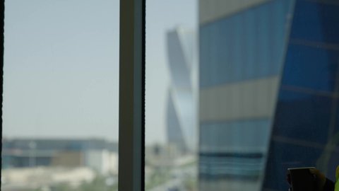 Working in the engineering field, women's office jobs and professions, the concept of engineering and architectural construction, a Saudi Arabian Gulf female engineer wearing a protective vest drinking coffee and looking through the window, a background of towers and skyscrapers, happy gestures
