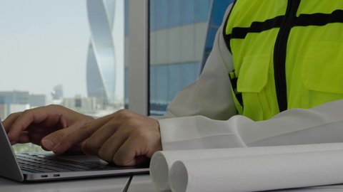 متابعة المشاريع والعمل، استخدام التقنيات الحديثة ومتطورة، الاهتمام بالتطور العمراني بسواعد المهندسين السعوديين, مهندس عربي خليجي سعودي ينجز المهام اليومية في المكتب عبر جهاز الحاسب المحمول ، مفهوم الهندسة والإنشاءات المعمارية، خلفية الأبراج وناطحات السحاب 