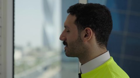 إدارة المشاريع الهندسية، مهن ووظائف سعودية، مفهوم الهندسة والإنشاءات المعمارية، تصوير مقرب من الخلف لمهندس عربي خليجي سعودي يرتدي سترة الحماية يتأمل معالم المدينة بفخر، خلفية أبراج وناطحات السحاب، 