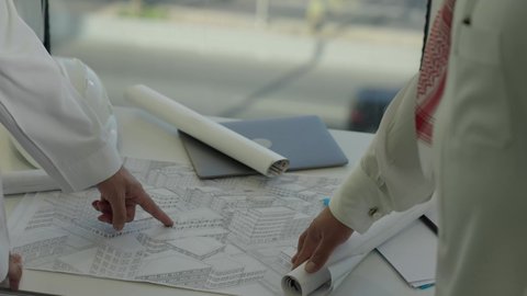 Planning and finalizing architectural plans, close-up of a Saudi Gulf team discussing the construction plan and accurately determining measurements, engineering work in the Kingdom of Saudi Arabia, companies specialized in construction and contracting workshops, following up on the implementation of previously drawn up plans