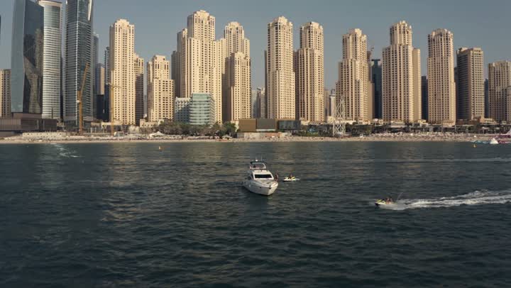 Sailing in the harbor and yacht marina in Dubai Marina, the architectural art of the buildings and structures overlooking the sea, the urban growth of towers and skyscrapers in the United Arab Emirates, famous tourist attractions in Dubai, the waterfront overlooking the Arabian Gulf coast