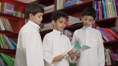 طلاب عربيين سعوديين خليجيين في المكتبة المدرسية، الاستمتاع بقراءة الكتب المدرسية، تأدية الواجبات المدرسية، التعليم في المملكة العربية السعودية