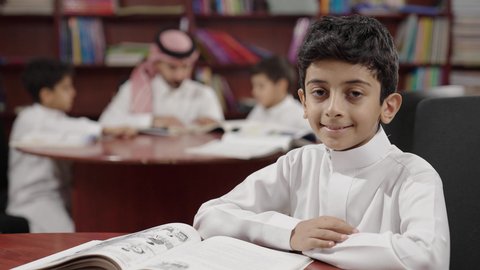 Performing school assignments, an Arab Saudi Gulf student in the school library, enjoying reading school books, education in the Kingdom of Saudi Arabia.