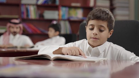 Education in the Kingdom of Saudi Arabia, an Arab Saudi Gulf student in the school library, enjoying reading school books, completing school assignments.