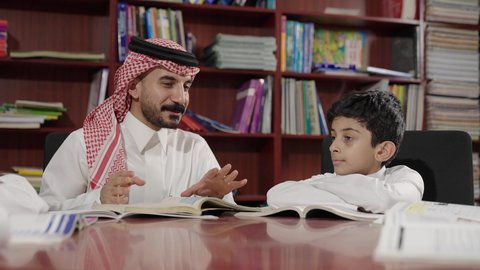 Spending enjoyable time, friendly dialogues between the teacher and the student, Arab Saudi Gulf students in the school library, enjoying reading school books, doing homework, education in the Kingdom of Saudi Arabia.