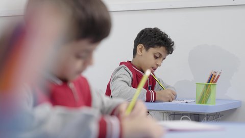 Preparation for the new school year, education in Saudi Arabia, completing school assignments, returning to school, a group of Arab Gulf Saudi students sitting in their seats and doing their homework.