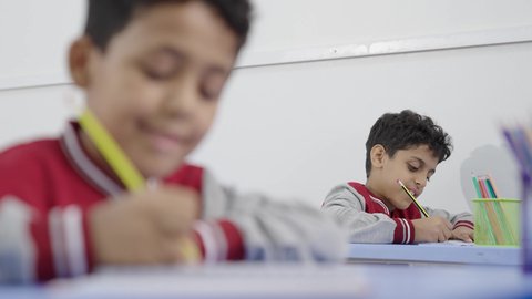 جودة التعليم في السعودية، معلم عربي خليجي سعودي يرتدي الثوب التقليدي والشماغ يقوم بمناقشة الدروس مع طلابه، المشاركة الفعالة للطلاب مع المدرسين، التربية والتعليم بالمناهج المقررة للتلاميذ، حوارات ودية بين الاستاذ والطلاب