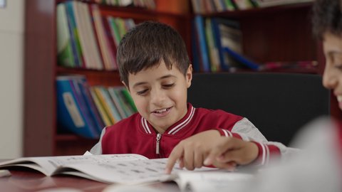 طلاب عربيين سعوديين خليجيين في المكتبة المدرسية، الاستمتاع بقراءة الكتب المدرسية، تأدية الواجبات المدرسية، التعليم في المملكة العربية السعودية