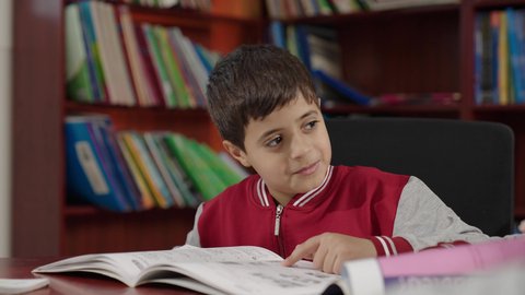 Performing school assignments, two Arab Saudi Gulf students in the school library, enjoying reading school books, education in the Kingdom of Saudi Arabia.
