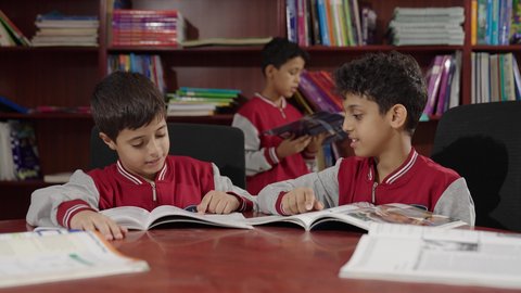 الاستمتاع بقراءة الكتب المدرسية، طلاب عربيين سعوديين خليجيين في المكتبة المدرسية، تأدية الواجبات المدرسية، التعليم في المملكة العربية السعودية