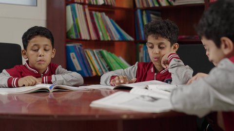 الاستمتاع بقراءة الكتب المدرسية، طلاب عربيين سعوديين خليجيين في المكتبة المدرسية، تأدية الواجبات المدرسية، التعليم في المملكة العربية السعودية