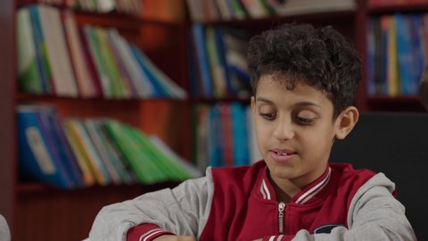 A developed educational school environment, Arab Saudi Gulf students sitting in the school library, enjoying reading books, the concept of self-directed learning, innovative schools, academic schools in the Kingdom of Saudi Arabia.