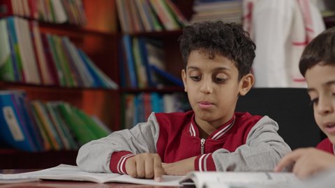 طلاب عرب سعوديون خليجيون يجلسون في المكتبة المدرسية، الاستمتاع بقراءة الكتب، مفهوم التعليم الذاتي, مكتبة المدرسة، بيئه مدرسيه تعليميه متطوره, المدارس المبتكره, جودة التعليم, مدارس أكاديميه في المملكة العربية السعودية