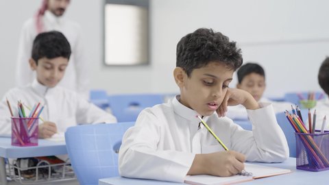 Preparation for the new school year, education in Saudi Arabia, completing school assignments, returning to school, a group of Arab Gulf Saudi students sitting in their seats and doing their homework.