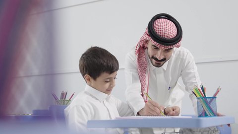 معلم عربي خليجي سعودي يرتدي الثوب التقليدي والشماغ يقوم بمناقشة الدروس مع طلابه، المشاركة الفعالة للطلاب مع المدرسين، جودة التعليم في السعودية، التربية والتعليم بالمناهج المقررة للتلاميذ، حوارات ودية بين الاستاذ والطلاب