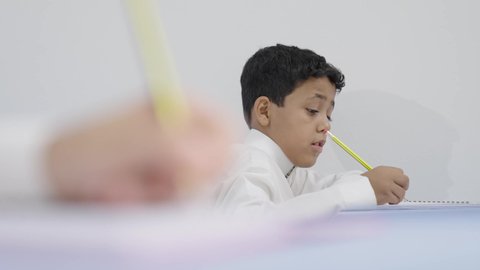 التعليم في السعودية،الإستعداد للعام الدراسي الجديد، تأدية الواجبات المدرسية، العودة إلى المدارس، مجموعة من الطلاب العربيين الخليجيين السعوديين يجلسون في مقاعدهم ويقومون بحل الواجب