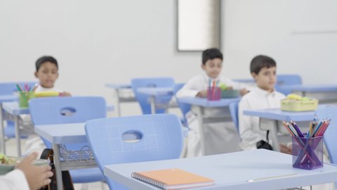 موسم العودة للمدارس،الاستمتاع بتناول الأطعمة الصحية في وقت الفسحة المدرسية، مجموعة من الطلاب العربيين الخليجيين السعوديين   يجلسون في مقاعدهم وأمامهم اللانش البوكس، الوجبات الغنية بالعناصر الغذائية الهامة لبناء الجسم