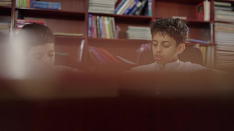 الاستمتاع بقراءة الكتب المدرسية، مجموعة من طلاب عربية سعودية خليجية في المكتبة المدرسية،  تأدية الواجبات المدرسية، التعليم في المملكة العربية السعودية