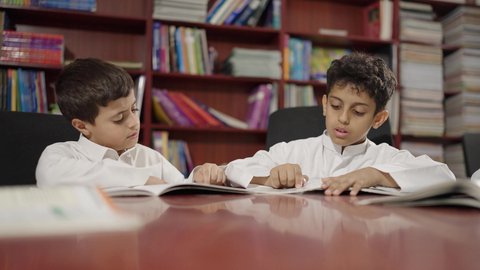 الاستمتاع بقراءة الكتب المدرسية، مجموعة من طلاب عربية سعودية خليجية في المكتبة المدرسية، تأدية الواجبات المدرسية، التعليم في المملكة العربية السعودية