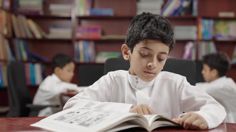 مجموعة من طلاب عربية سعودية خليجية في المكتبة المدرسية، الاستمتاع بقراءة الكتب المدرسية، تأدية الواجبات المدرسية، التعليم في المملكة العربية السعودية