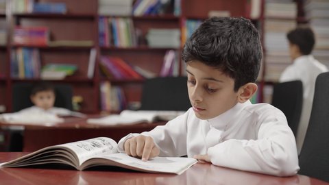 Enjoying reading school books, a group of Gulf Arab students in the school library, doing homework, education in the Kingdom of Saudi Arabia.