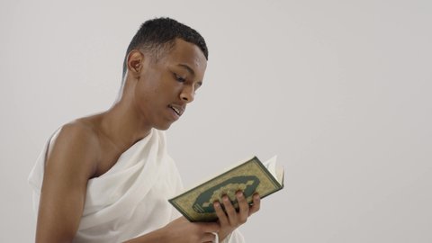 الشعور بالخشوع والطمأنينه, قراءة القرآن الكريم، بورتريه لرجل عربي خليجي سعودي يرتدي لباس الإحرام يحمل بيده المصحف الشريف و يقوم بالتلاوة منه, الإجتهاد في العبادة, التقرب الى الله تعالى, مفهوم أركان الإسلام، خلفية رمادي