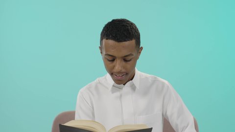 القراءة بتمعن وتركيز، التزود بالعلم والمعرفة، قضاء وقت الفراغ بالتثقيف والتعلم،  تحضير الدروس للوصول إلى النجاح, بورتريه لشاب عربي خليجي سعودي يرتدي الثوب التقليدي يقوم بقراءة كتاب, تطوير المناهج التعليمية في السعودية, خلفية أزرق
