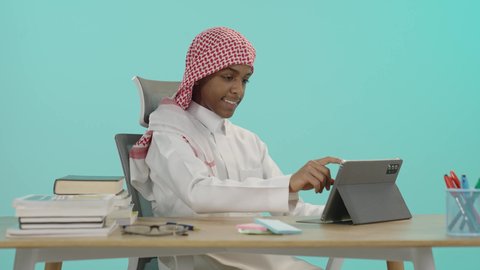 بيئة دراسية مريحة, ادخال التقنية والتكنولوجيا بالتعليم، بورتريه لطالب عربي خليجي سعودي يرتدي الشماغ والثوب التقليدي يقوم باستخدام التابلت, مفهوم الاجتهاد والتفوق, الاستعداد للعام الدراسي الجديد، خلفية زرقاء