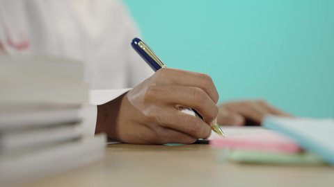 الإجابة على الأسئلة بدقة وتركيز، كتابة وتسجيل الملاحظات، المذاكرة والاجتهاد والدراسة، قضاء الوقت بالتعلم والتثقف، بورتريه مقرب ليد طالب عربي خليجي سعودي يقوم بالكتابة و التدوين, مفهوم العمل الجاد والتفوق, المناهج والمواد التعليمية, خلفية زرقاء