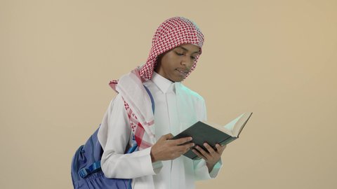 تحضير الدروس للوصول إلى النجاح, الاستعداد للعام الدراسي الجديد، مراجعة الدروس اليومية, بورتريه لشاب عربي خليجي سعودي يرتدي الثوب التقليدي و شماغ و حقيبة ظهر يقوم بقراءة كتاب, تطوير المناهج التعليمية في السعودية, خلفية بيج