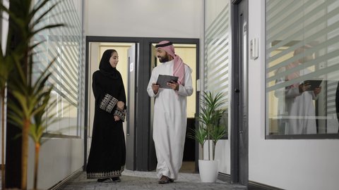 كتابة وتسجيل البيانات والملاحظات، تطوير خطة وآلية العمل، التحقق والتدقيق في العروض المالية، إنجاز الأعمال المكتبية، التفاهم والتعاون بين الزملاء لتحقيق الاهداف، رجل عربي خليجي سعودي يرتدي الزي التقليدي و الشماغ يقوم بشرح المهام لزميلته داخل الشركة