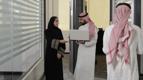 تبادل الأفكار والخبرات لتطوير استراتيجيات العمل، زميلين عربيين خليجيين سعوديين  يسيريان داخل الشركة يقومان بإنجاز المهام عبر الحاسوب المحمول، التعاون وتوحيد الجهود لتحقيق أهداف الشركة، دمج التقنية و التكنولوجيا في العمل