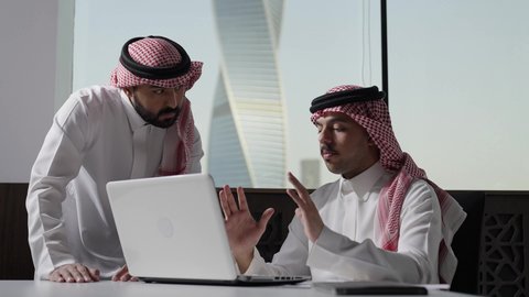 ادارة العمل باستخدام الحاسب المحمول، اجتماع رجلان عربيان سعوديان خليجيان يرتديان الزي التقليدي و الشماغ في مقر الشركة، مناقشة و شرح الدلالات و الرموز الاحصائية، بيئة العمل السعودي، الوحده والعمل الجماعي، تحقيق اهداف الشركة، تطوير العمل وحل المشكلات، مهن ووظائف سعودية مكتبية