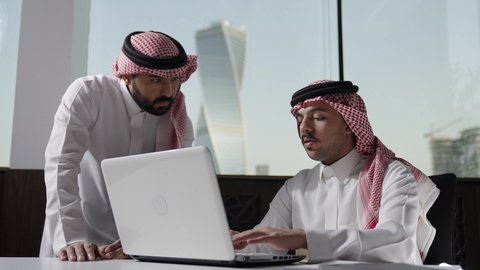 اجتماع رجلان عربيان سعوديان خليجيان يرتديان الزي التقليدي و الشماغ في مقر الشركة، ادارة العمل باستخدام الحاسب المحمول، مناقشة و شرح الدلالات و الرموز الاحصائية، بيئة العمل السعودي، الوحده والعمل الجماعي، تحقيق اهداف الشركة، تطوير العمل وحل المشكلات، مهن ووظائف سعودية مكتبية