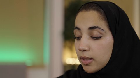 Spending time reading, learning, and educating oneself, the culture of self-learning, a close-up shot of a Saudi Arabian Gulf woman in a hijab reading something, the hobby of reading and exploration.