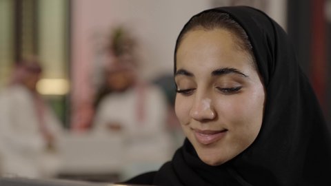 The use of modern technological devices, the concept of completing projects and tasks remotely, browsing social media sites, communicating with family and friends via the iPad, a close-up shot of a Saudi Arabian Gulf woman wearing a black abaya who is using a tablet.