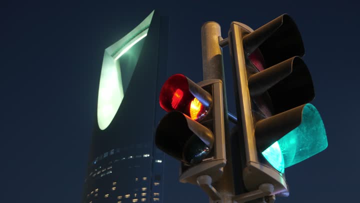 معالم سياحية مشهورة لجذب الزوار من شتى أنحاء العالم، تصوير مقرب للإشارة المرورية، الفن الهندسي المعماري المتطور لمبنى برج المملكة المضاء في  العاصمة السعوديه, تنمية المنشآت الهندسية الحديثة في المملكة، ناطحات السحاب في وقت الليل في مدينة الرياض